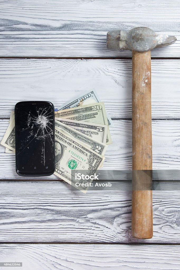 Modern broken mobile phone and money on white wooden background. Modern broken mobile phone and money on white wooden background. Copy space. Top view 2015 Stock Photo