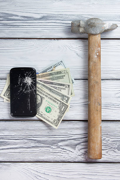 Modern broken mobile phone and money on white wooden background. Modern broken mobile phone and money on white wooden background. Copy space. Top view broken digital tablet note pad cracked stock pictures, royalty-free photos & images