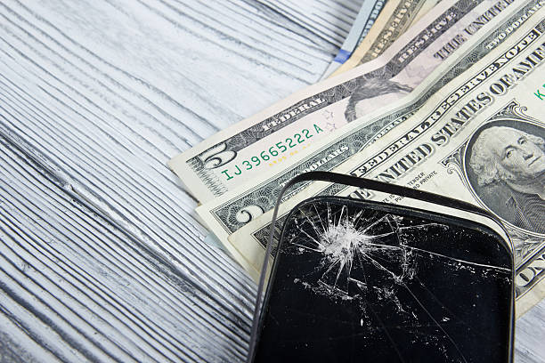 istock Modern broken mobile phone and money on white wooden background. 484622588