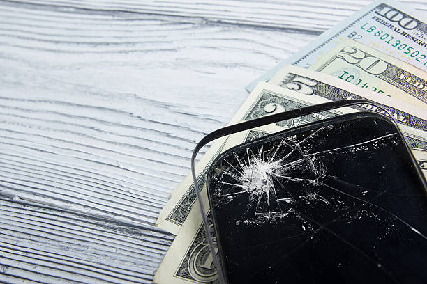 istock Modern broken mobile phone and money on white wooden background. 484622626