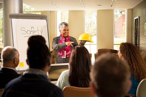 Safety in the workplace. Presentation with office workers. Business woman gives safety presentation at office. Multi-ethnic group of professionals. health and safety stock pictures, royalty-free photos & images