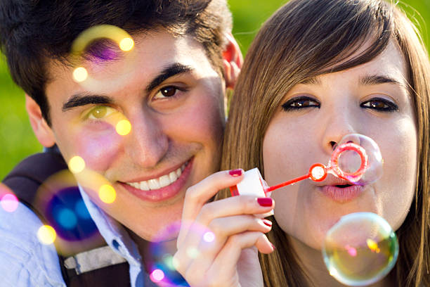 istock Young couple having fun with soap bubbles in the park 484624293