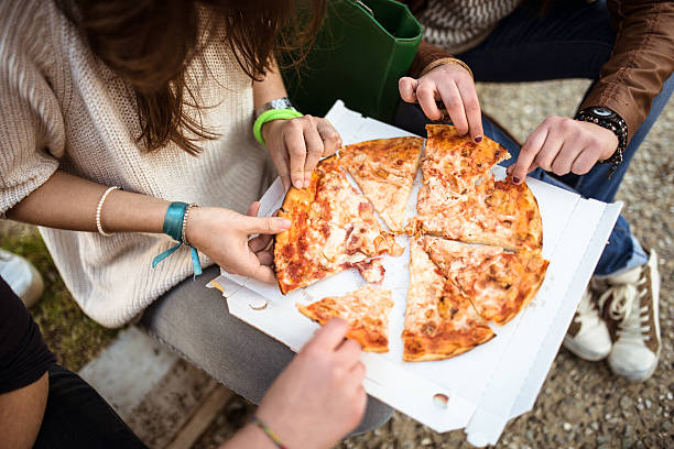 istock group of friends eating pizza togetherness 484624817