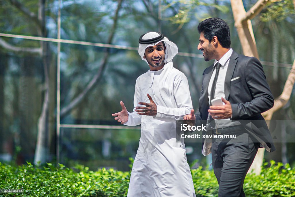 Middle Eastern businessmen talking in the street Middle Eastern businessmen talking in the street about business, one is wearing the typical dishdasha and the other a suit. United Arab Emirates Stock Photo