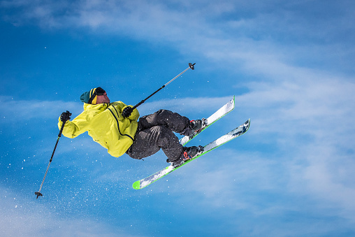 Young male freestyle skier performing attractive trick in the air.