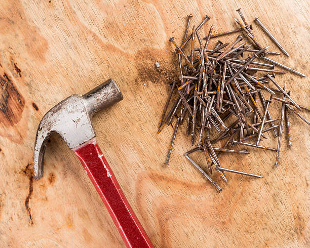 istock Hammer head and nails on a wooden table 484630184