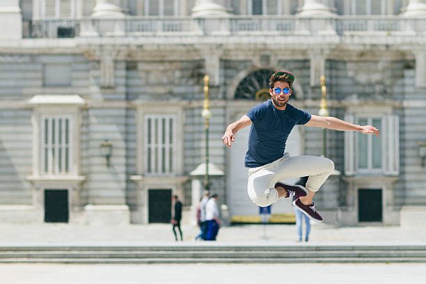 Hipster guy jumping outside Palace buildings, Madrid