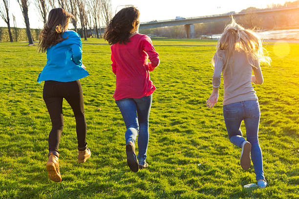 istock Three girls running in the park 484649789
