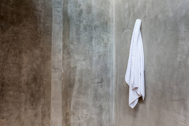istock White towel is hanging on the exposed concrete wall. 484650088