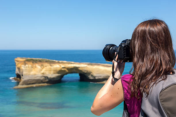 donna fotografo assunzione di foto con fotocamere dslr sulla spiaggia - australia photographing camera beach foto e immagini stock