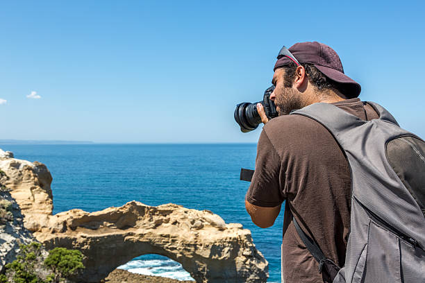 istock Man Photographer Taking Picture with DSLR Camera on Beach 484650301