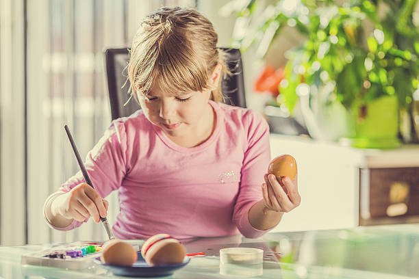 istock Little girl painting Easter eggs at home 484652576
