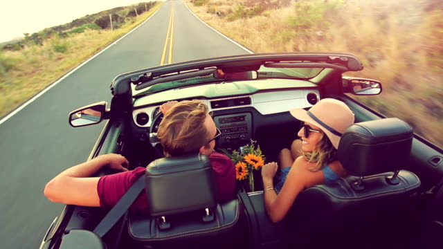 Attractive Young Couple Driving Convertible Car