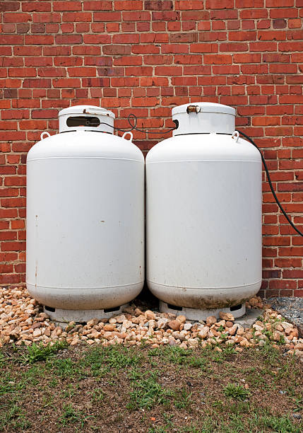 istock Two Propane Tanks Canisters Aginst Brick Wall 484655116