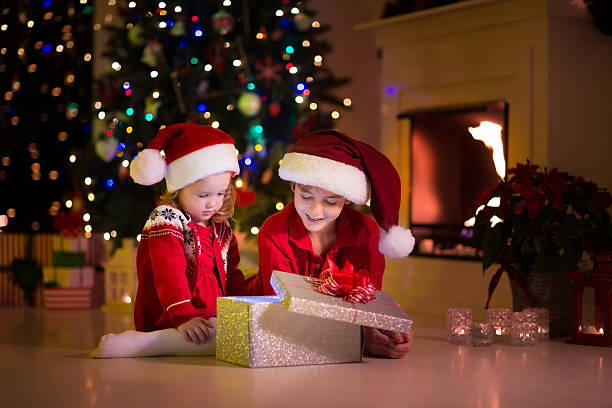 istock Kids opening Christmas presents at fireplace 484659030