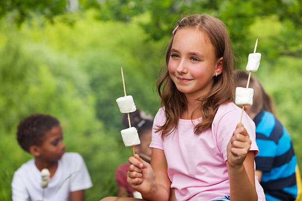 istock Smiling girl holding marshmallows near tent 484664422