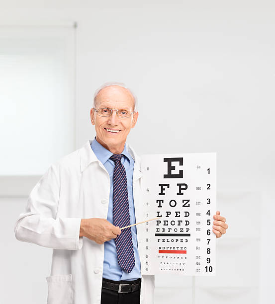 istock Mature optician holding an eye chart and pointing on it 484664446