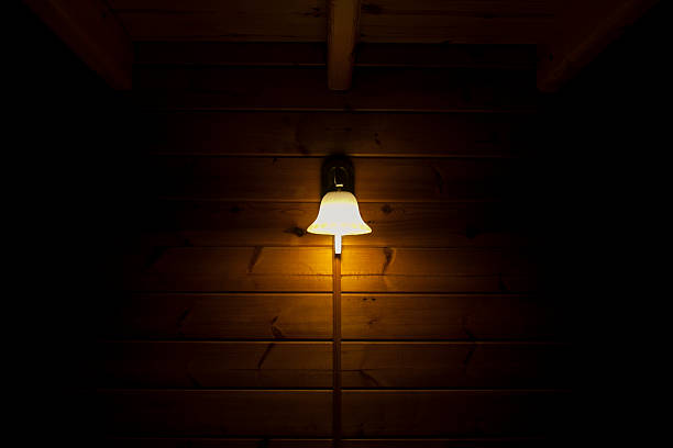 Classic table lamp with turned on bulb under lampshade is on table with cloth.  Authentic fine dining European atmosphere.