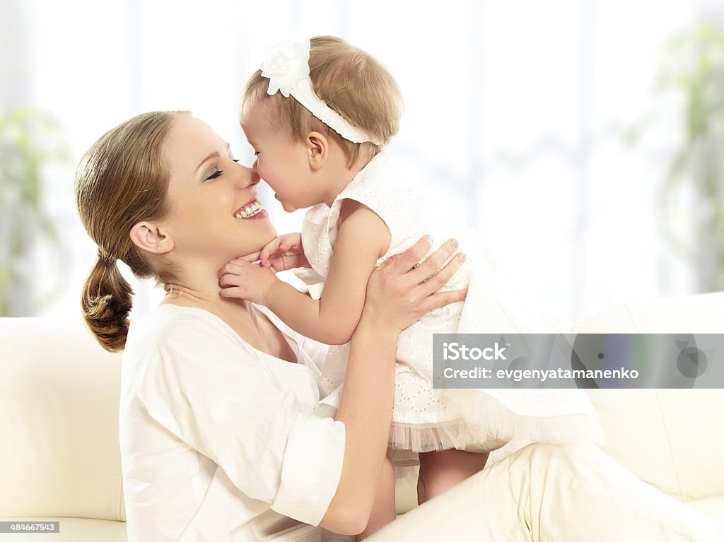 happy family. Mother and baby daughter plays, hugging, kissing happy family. Mother and baby daughter plays, hugging, kissing at home on the sofa Adult Stock Photo