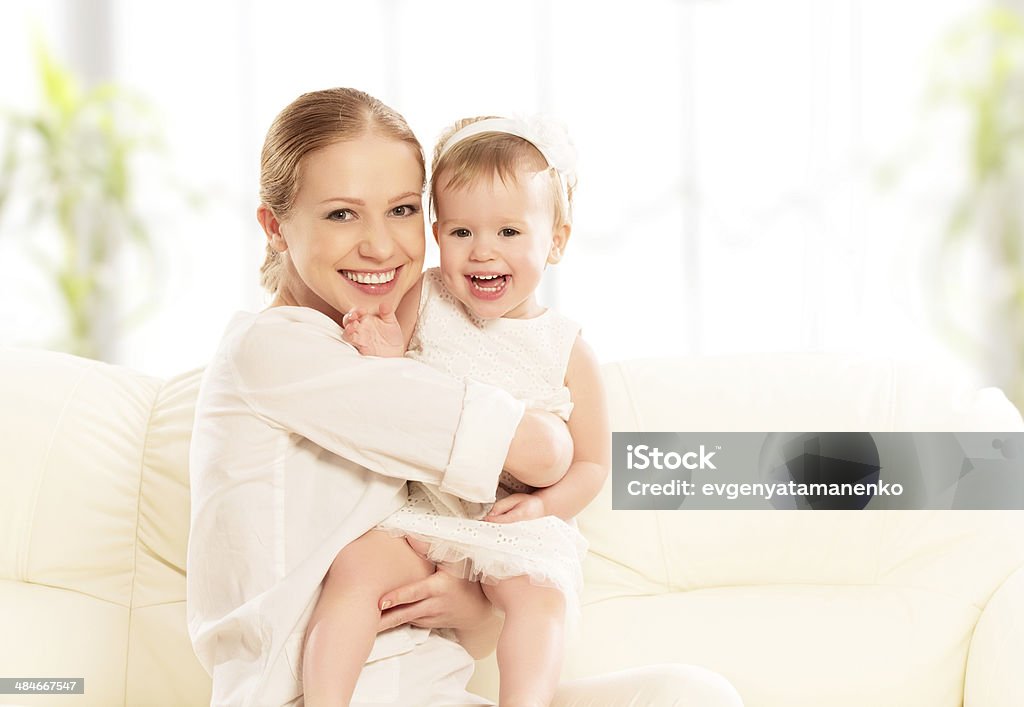 happy family. Mother and baby daughter plays, hugging, kissing happy family. Mother and baby daughter plays, hugging, kissing at home on the sofa Adult Stock Photo