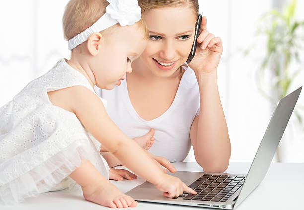 istock mother and baby daughter works with  computer, phone 484667575