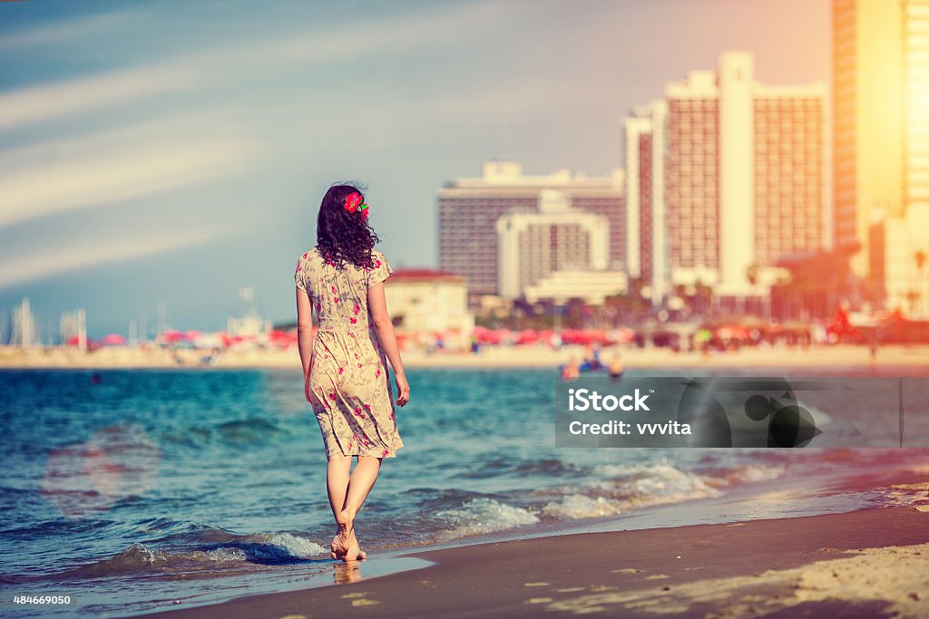 Young woman walking on the beach in Tel Aviv, Israel Young woman walking back to camera at sunset on the beach in Tel Aviv, Israel Israel Stock Photo