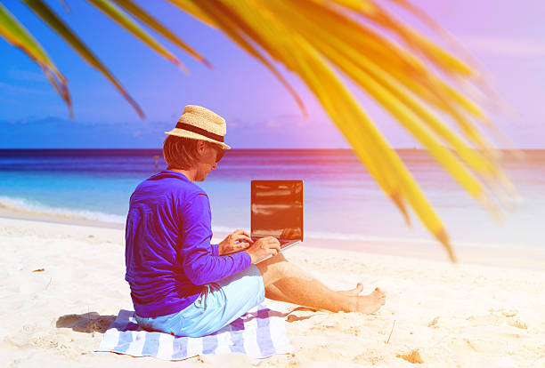 istock man with laptop on tropical sand beach 484669768