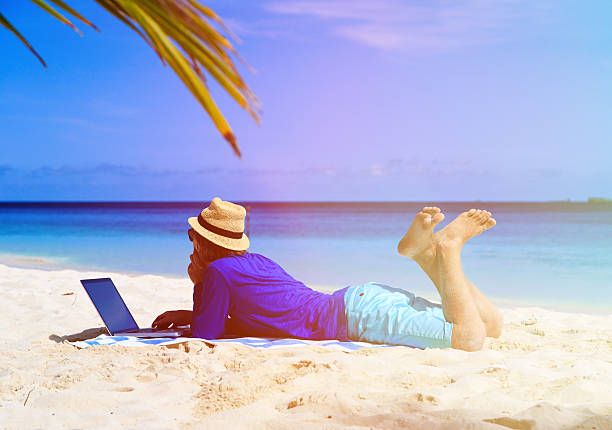 istock man with laptop on tropical sand beach 484669772