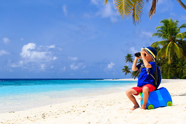 istock little boy travel on summer tropical beach with suitcase 484669982