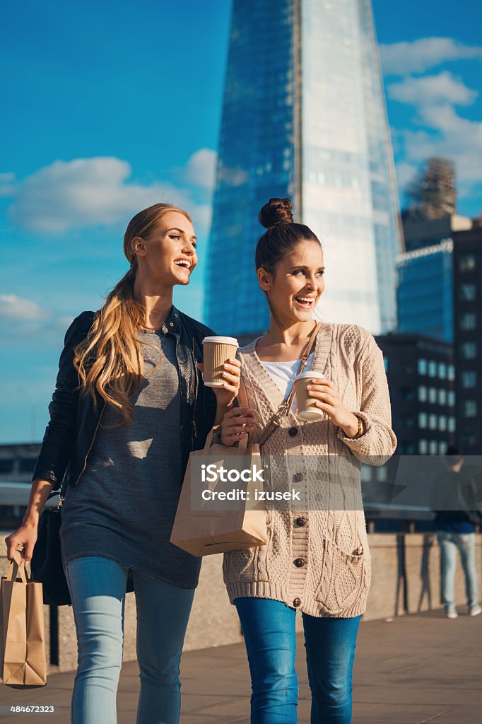 London tourists Outdoor portrait of two young happy women walking with take away food and coffee in hands, with The Shard Tower in the background. Coffee - Drink Stock Photo