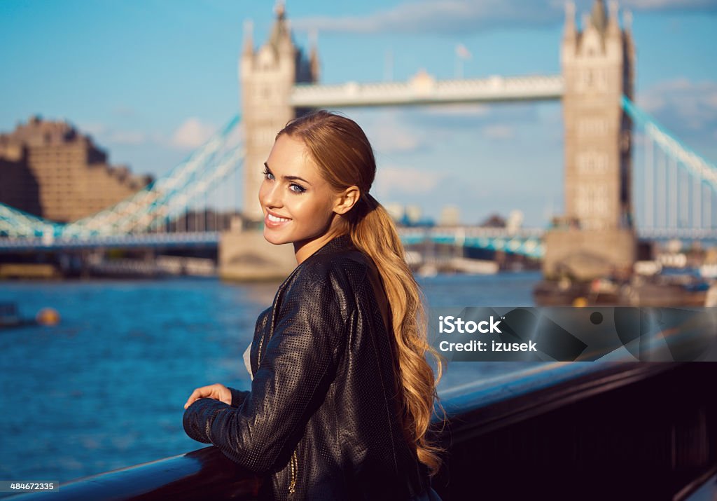 London sightseeing Outdoor portrait of beautiful young woman looking at Thames River with Tower Brigde in the background. Beautiful Woman Stock Photo