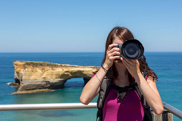 donna fotografo assunzione di foto con fotocamere dslr sulla spiaggia - australia photographing camera beach foto e immagini stock