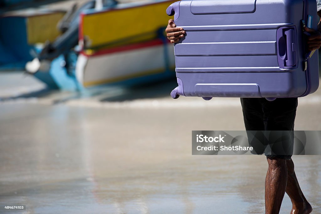 Man carrying luggage Unrecognizable man carrying purple luggage on the beach next to the boat  30-39 Years Stock Photo