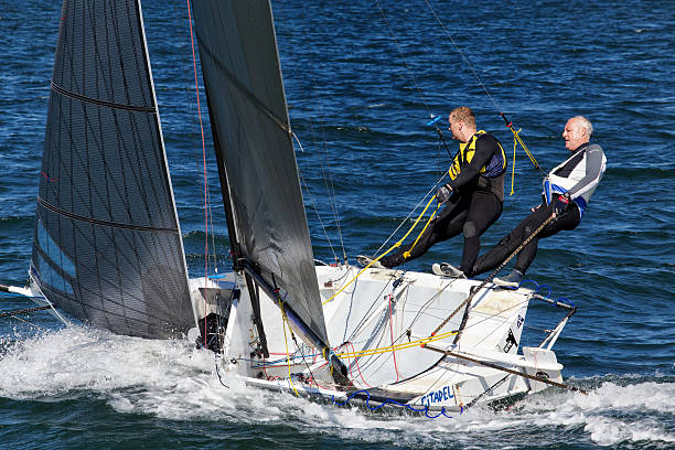 Felixstowe, Suffolk, England - June 11, 2016: Capsized Laser Sailing Dinghy with man trying to right it, in the sea at Felixstowe Suffolk England.