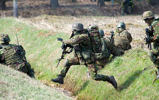 Geesteren, Netherlands - March 25, 2013: A camouflaged soldier is jumping over a ditch during a training of special forces of the Dutch army on a cold day in March. The training was called 'Cerberus Guard' and about a thousand soldiers and the air force worked together. The training took place in the open field between farmes and in small villages, March 25, 2013 in the Netherlands.