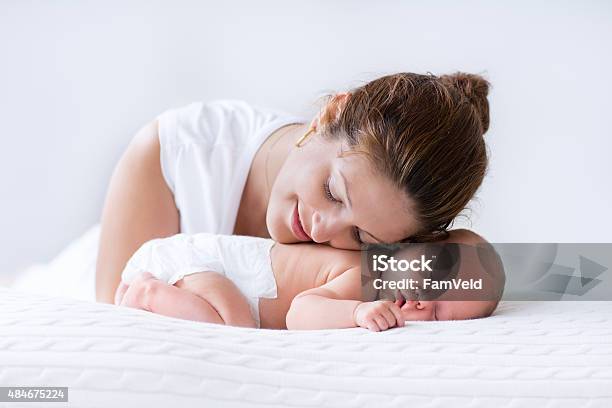 Young Mother And Newborn Baby In White Bedroom Stock Photo - Download Image Now - Mother, Baby - Human Age, Diaper