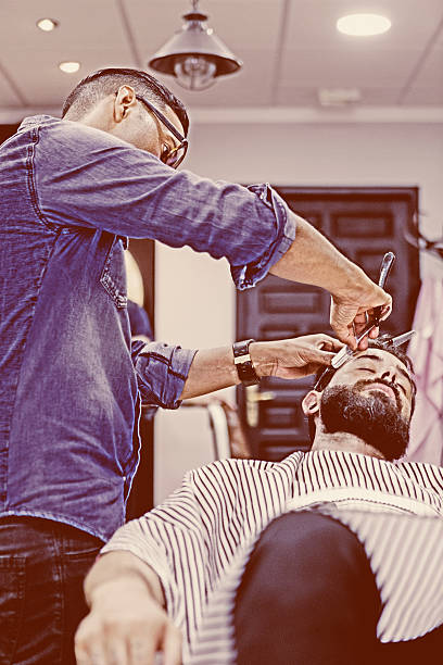 istock young male hairstylist on a beard shaving session 484676316