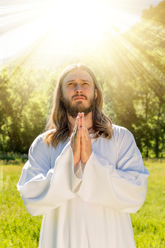 Stock photo of Jesus Christ praying with divine light ray behind him