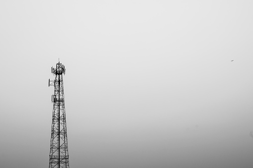 A single telecommunication pole on the sky background with black and white tone