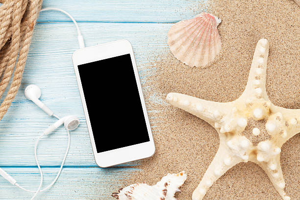 istock Smartphone on wood and sea sand with starfish and shells 484683590