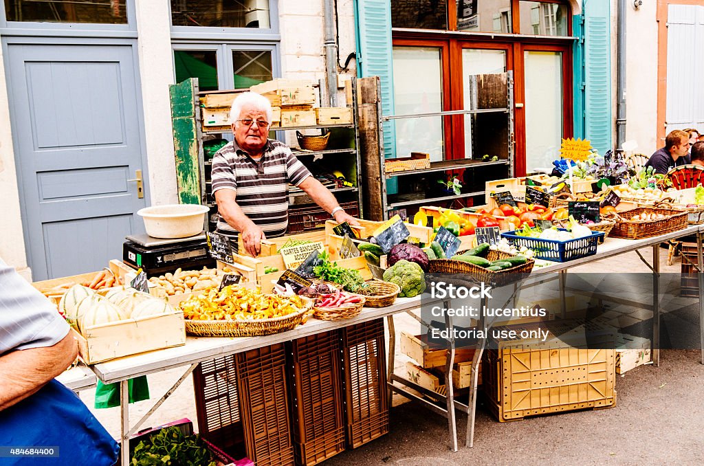 Saturday market in France Tournus, France - July 25, 2015: Stallholder on the Rue Desire Mathivet at the farmer's market at Tournus in France. The market at Tournus is often very busy in the summer months and brings in tourists from far and wide. 2015 Stock Photo