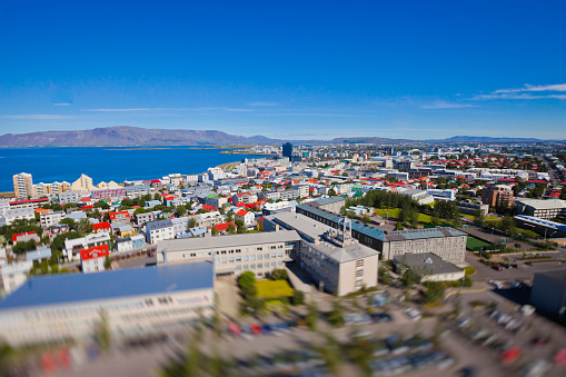 Beautiful summer super wide-angle aerial view of Reykjavik, Iceland with harbor and skyline mountains and scenery beyond the city, seen from the observation tower of hallgrimskirkja church with blue sky in sunny day.