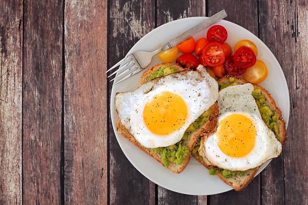 istock Healthy avocado, egg toasts with tomatoes on rustic wood background 484687380