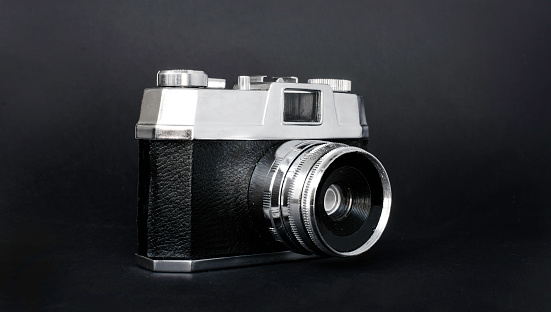 An old photography camera is isolated in a studio shot on a black background with copy space. This horizontal colour image is a symbol for art and old photographic equipment. 