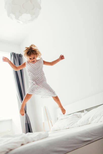 istock Little Girl Jumping On The Bed. 484701294
