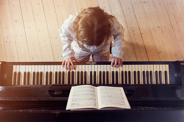 oben blick auf jungen mädchen spielen klavier im sonnenlicht zimmer - practicing piano child playing stock-fotos und bilder