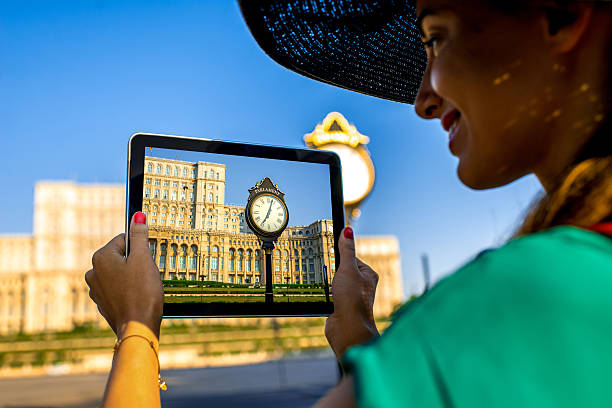 Female hands photographing with digital tablet parliament building in Bucharest, Romania