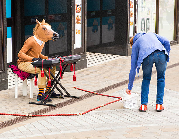 Leeds, UK - July 24, 2015:  A man busking on Briggate in Leeds city centre. Performer is playing a keyboard whilst wearing a horses head.