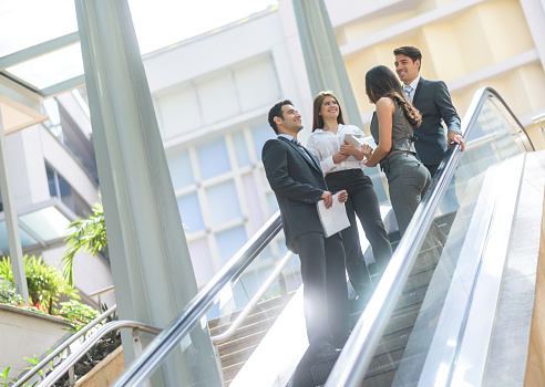 Successful group of business people talking at the office and climbing the escalators