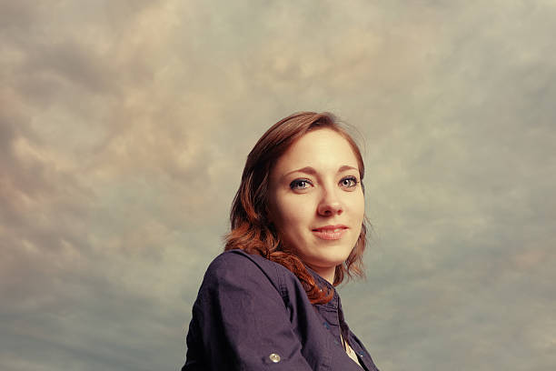 istock Red head women smiling against cloudy evening sky 484711688